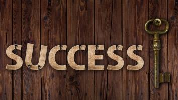 Brown wooden background with success written next to a metal key 