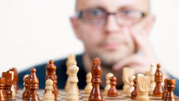 A man looking at a chess board and thinking about the next move.