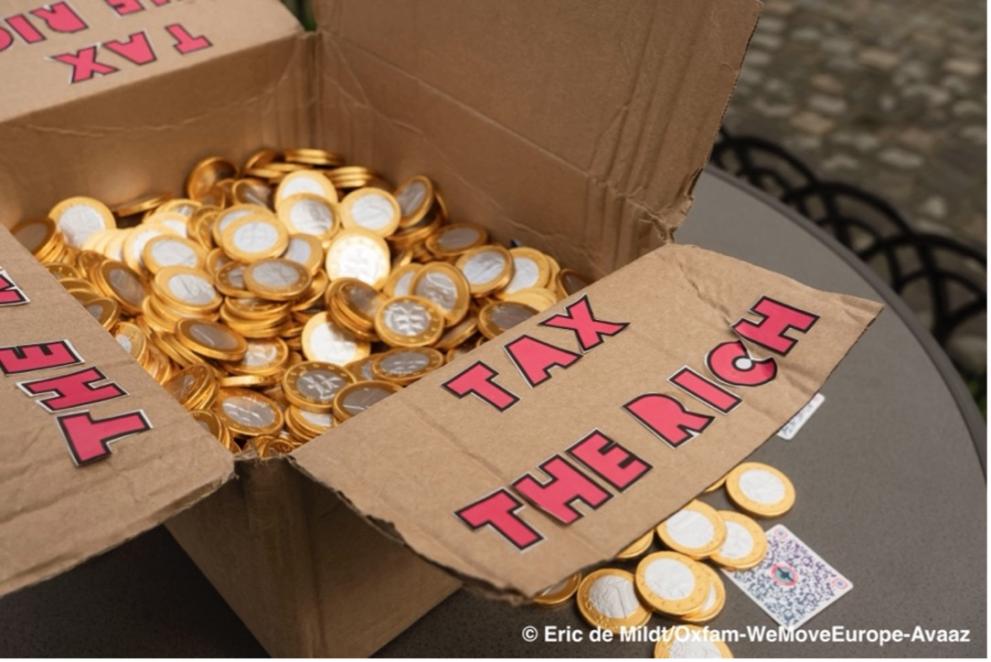 Cardbox with "tax the rich" on the side filled with coins 