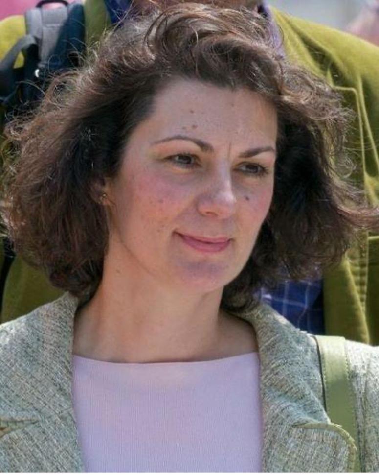 Women with brown hair wearing a grey blazer and lilac shirt