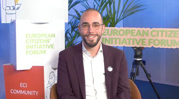 Matteo Cadeddu, member of the group of organisers of My Voice, My Choice in a suit sits during an interview  for the ECI Forum during ECI Day.